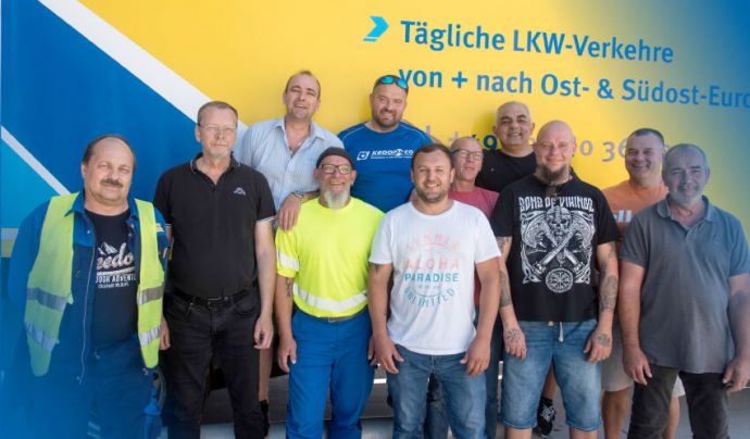 Kroop Leitgedanke Gut gelaunte Mitarbeiter vor LKW-Plane